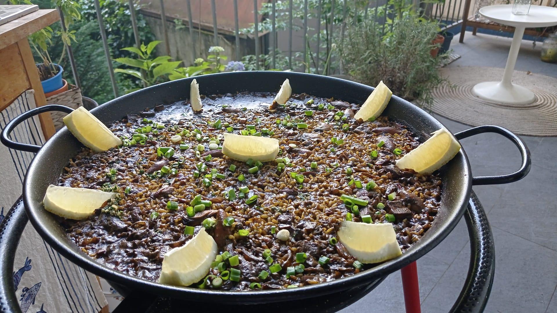 Dunkle Reispaella mit Zitronenspalten garniert