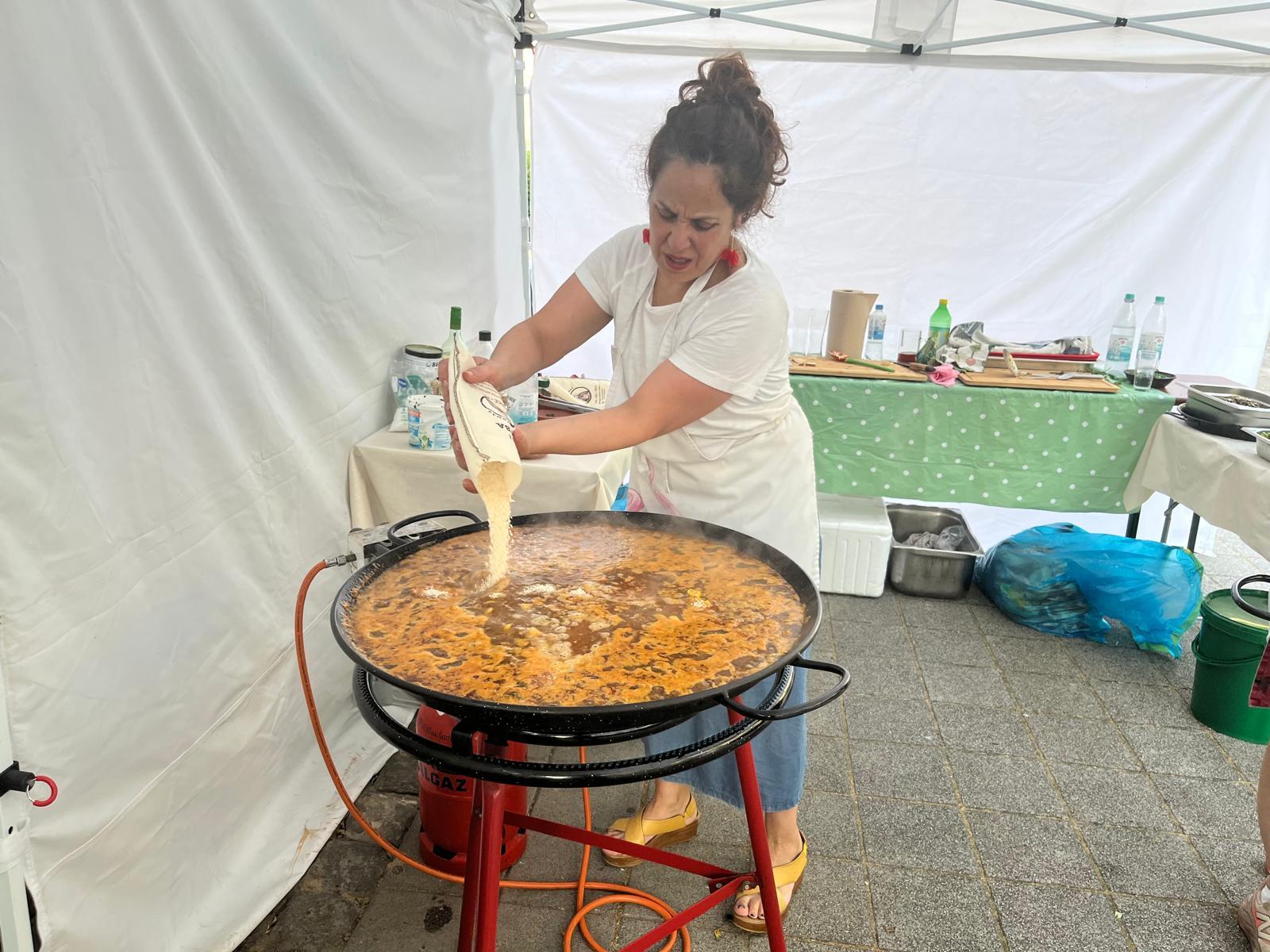 Julia Sanchez gießt Reis in die Paella-Pfanne bei einer Firmenfeier